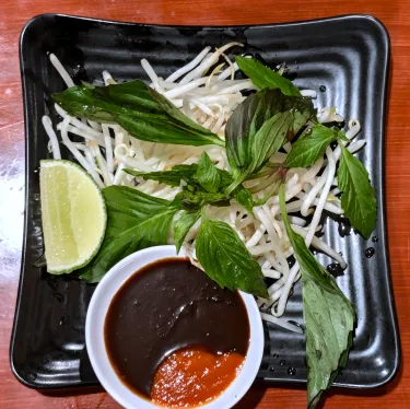 A plate of herbs used to top beef noodle soup