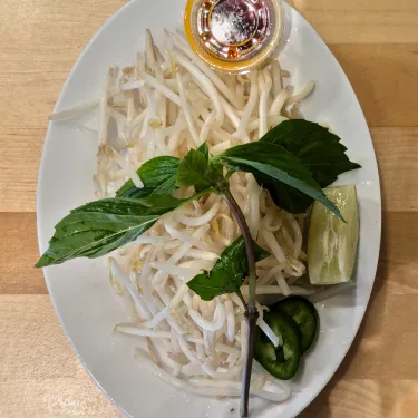 A plate of herbs used to top beef noodle soup