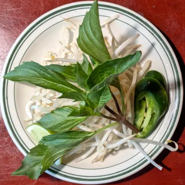 A plate of herbs used to top beef noodle soup