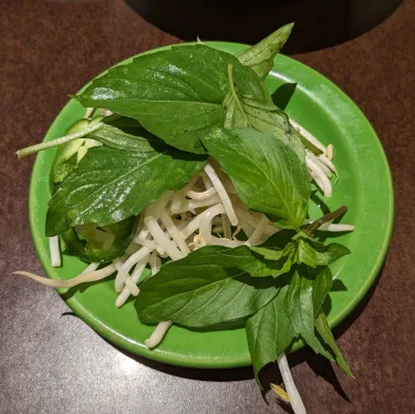 A plate of herbs used to top beef noodle soup