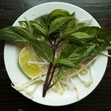 A plate of herbs used to top beef noodle soup