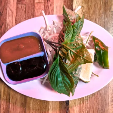 A plate of herbs used to top beef noodle soup