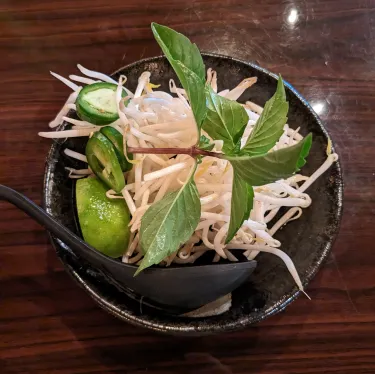 A plate of herbs used to top beef noodle soup