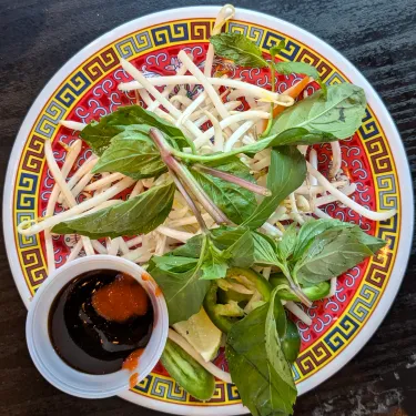 A plate of herbs used to top beef noodle soup